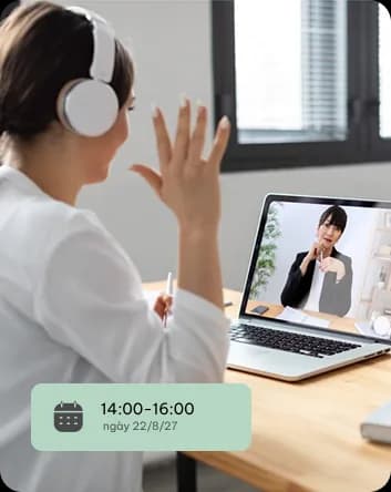 Một buổi tư vấn trực tuyến: thân chủ đeo tai nghe trò chuyện với chuyên gia qua laptop, kèm thẻ ghi khung giờ hẹn